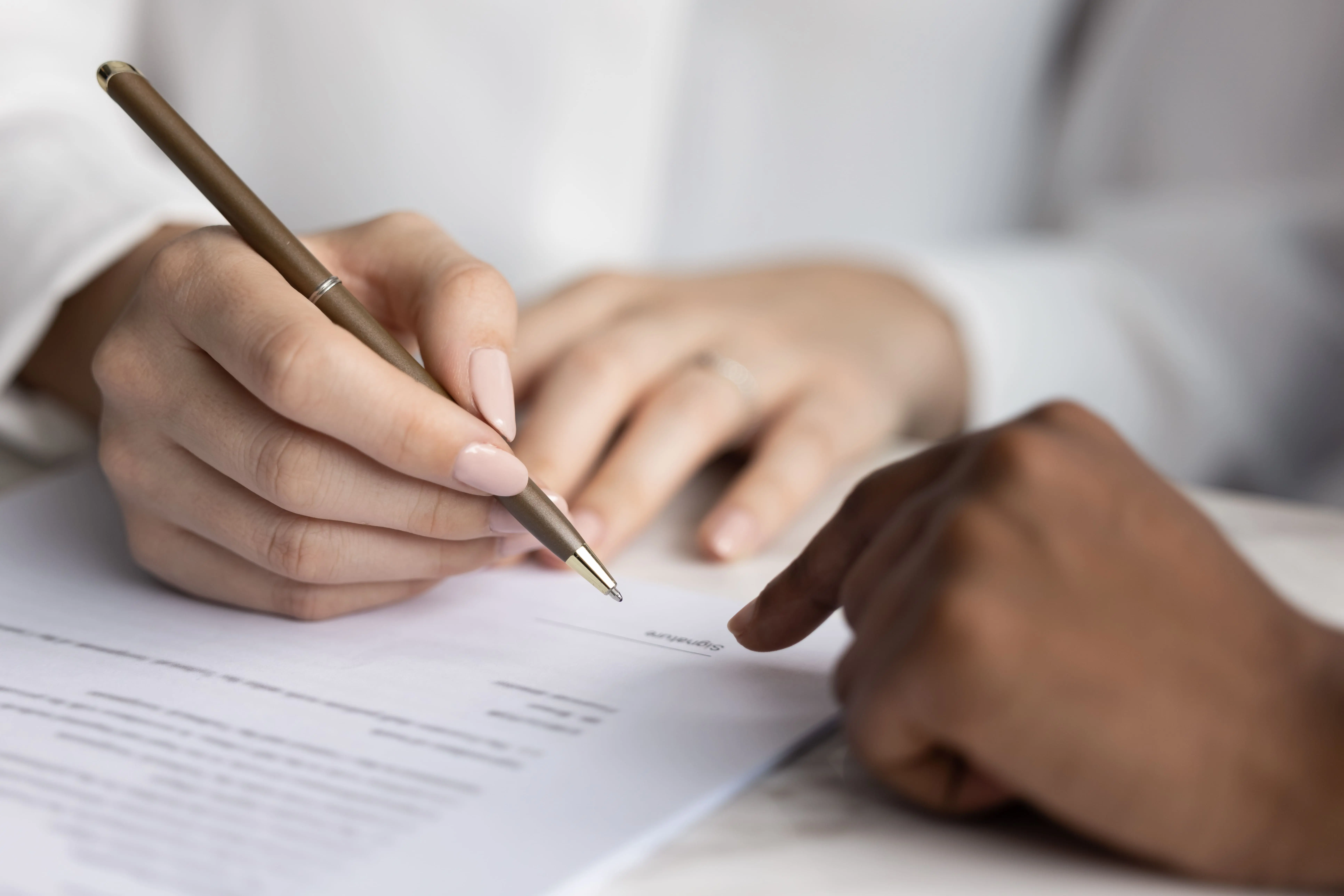 A person's hands shown signing a document, representing the legal review of Colorado employment contracts.