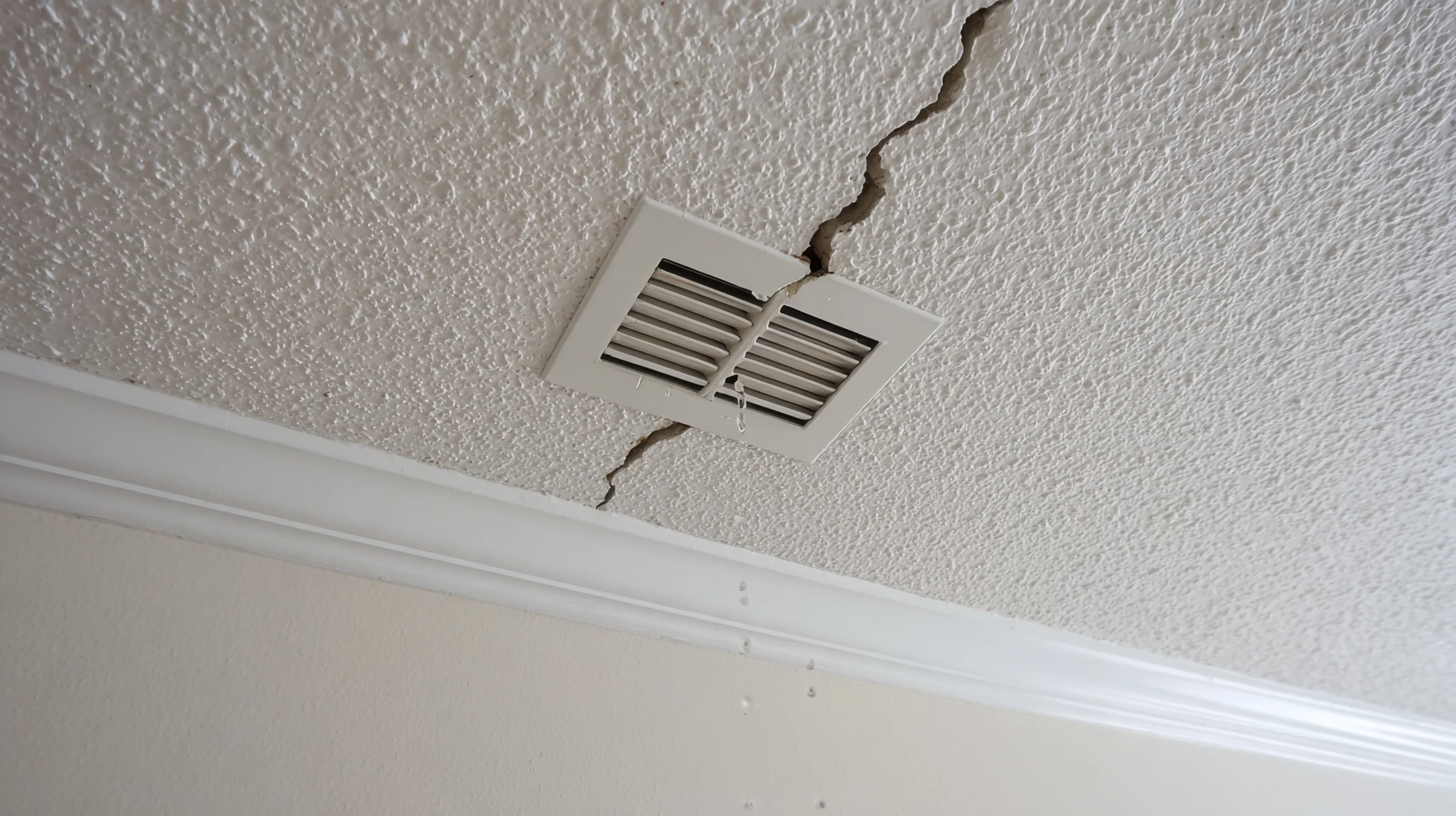Large cracks in a ceiling next to an air vent, symbolizing structural defects  evaluated by our construction defect attorneys.