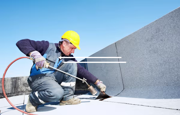 Roofer installing torch-down membrane on a flat roof, a waterproofing process critical to preventing leaks evaluated by commercial property construction defect attorneys.